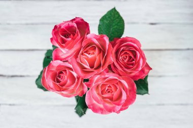 Beyaz ahşap bir masa kürsüye pembe Gül vazo. Üstten Görünüm