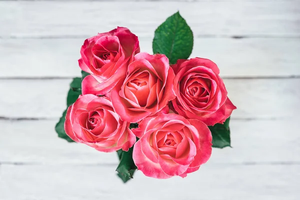 Beyaz ahşap bir masa kürsüye pembe Gül vazo. Üstten Görünüm