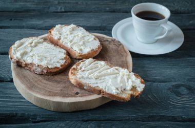 Siyah ahşap bir masa üzerinde krem peynirli sandviç ev yapımı kahvaltı. Sandviç ile ahşap stand.