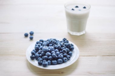 Yaban mersini ve ahşap bir masa üzerinde bir bardak yoğurt ile rustik sağlıklı kahvaltı. Cam olgun çilek ile ev yapımı yoğurt
