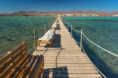Pier deniz tatil şezlong şezlong ile. Yaz tatili. Turkuaz su ile açık denizde görüntüleyin. Egzotik bir ülkede bir deniz sahil şeridi, yaz tatili.