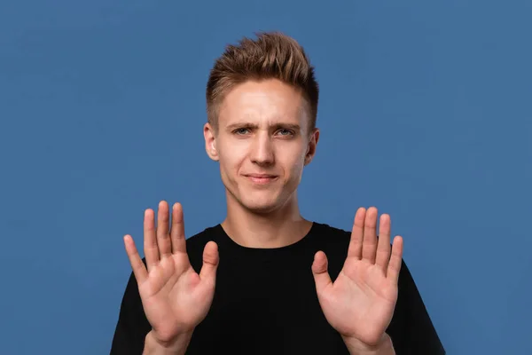 Przystojny młody mężczyzna w czarnej koszulce pokazuje gest stop obiema rękami. — Zdjęcie stockowe