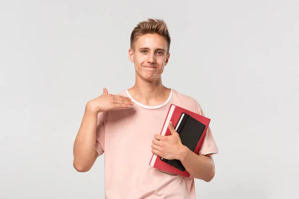 Przystojny młody człowiek w różowej koszulce z książkami i aktami wyrażającymi gest bycia zmęczonym. — Zdjęcie stockowe