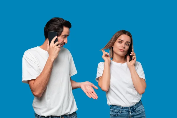 Blonde Frau und brünetter Mann in weißen T-Shirts und blauen Jeans telefonieren. — Stockfoto