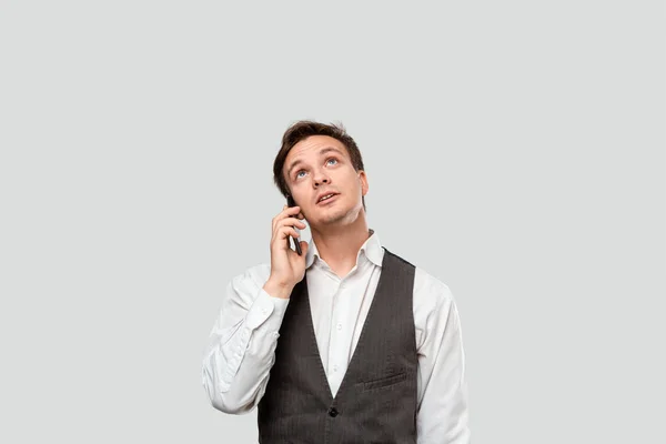 Jovem empresário de camisa branca e colete cinza falando em um smartphone . — Fotografia de Stock
