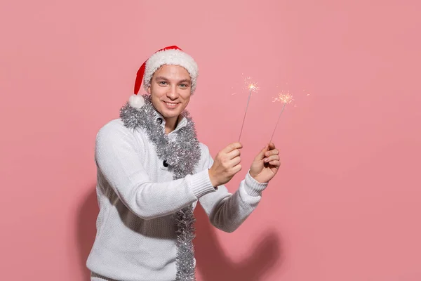 Homem excitado com uma camisola branca e chapéu vermelho de Papai Noel segurando luzes de Bengala celebrando Cristmas e Ano Novo — Fotografia de Stock