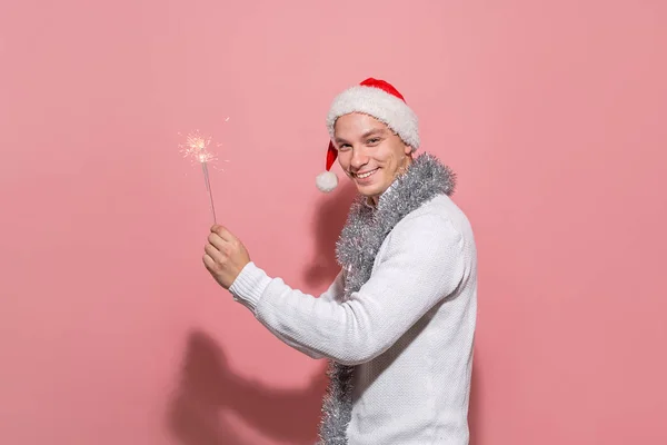 Homem excitado com uma camisola branca e chapéu vermelho de Papai Noel segurando luzes de Bengala celebrando o Natal e Ano Novo . — Fotografia de Stock