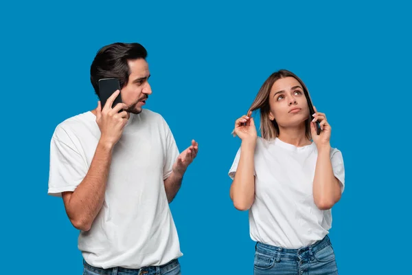 Blonde Frau und brünetter Mann in weißen T-Shirts und blauen Jeans telefonieren. — Stockfoto