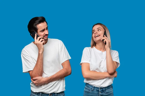 Eine blonde Frau und ein brünetter Mann in weißen T-Shirts und blauen Jeans unterhalten sich am Telefon.. — Stockfoto