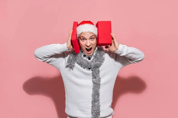 Homem com uma camisola branca e chapéu vermelho Papai Noel está animado para ter tantos presentes de Natal . — Fotografia de Stock