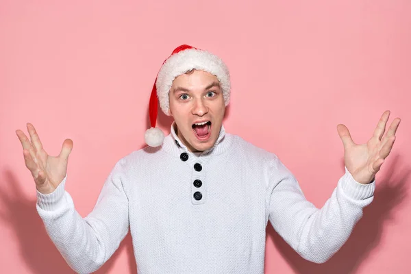 El hombre con un suéter blanco y un sombrero rojo de Santa Claus está muy emocionado de celebrar la Navidad y el Año Nuevo. . —  Fotos de Stock