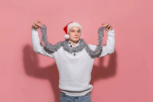 Homem feliz em uma camisola branca, chapéu de Papai Noel e trumpery está animado para celebrar o Natal e Ano Novo . — Fotografia de Stock