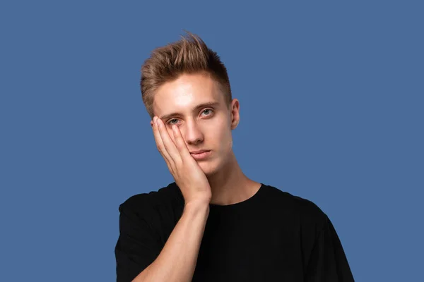 Trött ung man i svart t-shirt håller hand på huvudet täcker ansikte isolerad över grå nackground. — Stockfoto