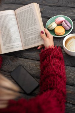 Bir Fransız kafesinde kapuçino içip kitap okuyan bir kadın..