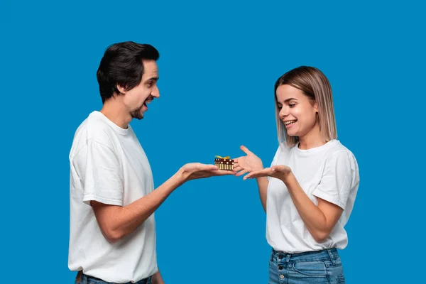 Novio dando regalo a su novia aislado sobre fondo azul. Concepto de amor — Foto de Stock