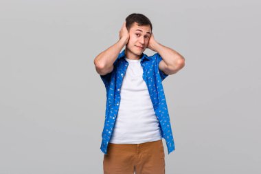 Kulakları elleriyle kapatan genç bir adam. Üç bilge maymunun hareketi.