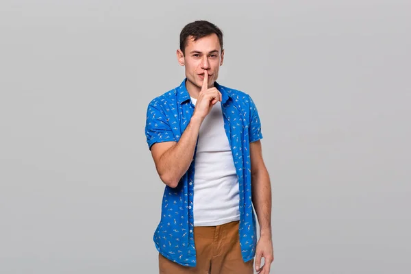 Hombre en una camiseta blanca y camisa azul sosteniendo el dedo pidiendo guardar silencio . —  Fotos de Stock