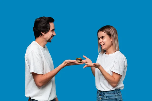 Novio dando regalo a su novia aislado sobre fondo azul. Concepto de amor — Foto de Stock