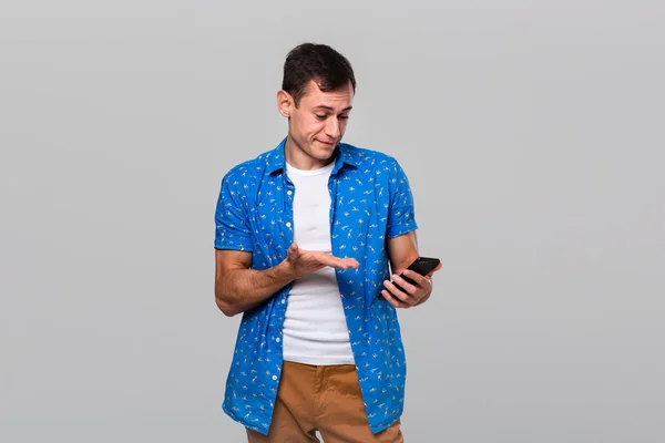Verbaasde man kijkt naar het scherm van een smartphone wordt geschokt. — Stockfoto