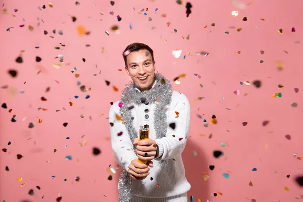 Opgewonden man in een witte trui viert Kerstmis en Nieuwjaar met confetti — Stockfoto