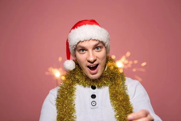 Homem de camisola branca e chapéu vermelho de Papai Noel segurando luzes de Bengala comemorando o Natal e o Ano Novo . — Fotografia de Stock