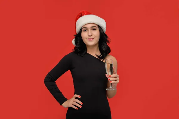漂亮的黑发姑娘，身穿黑色衣服，戴着圣诞礼帽，手里拿着一杯香槟. — 图库照片