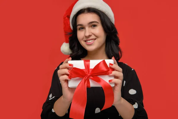 身穿婚纱、头戴圣诞礼帽的女人笑着拿着装有红丝带的白色圣诞礼盒 — 图库照片