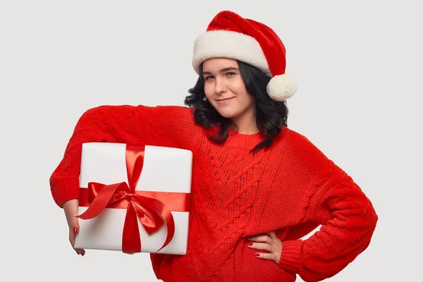 Brünettes Mädchen in rotem Pullover und Weihnachtsmann-Hut mit weißer Geschenkbox und roter Schleife — Stockfoto
