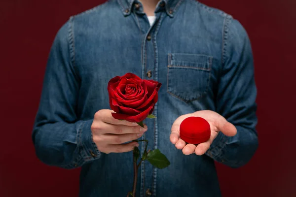 Jeune homme faisant la demande en mariage tenant une rose rouge et boîte avec bague de fiançailles — Photo