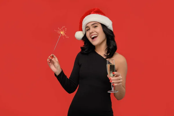 漂亮的黑发姑娘，身穿黑色连衣裙，头戴圣诞帽，手里拿着一杯香槟和一盏灯. — 图库照片