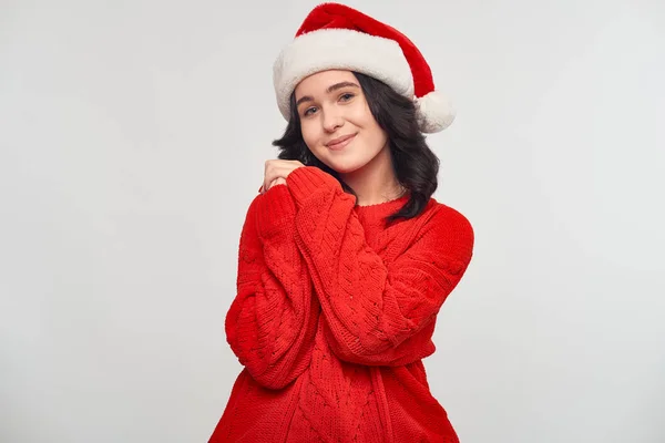 Girl in a red sweater and Santa Claus hat holding fingers crossed dreaming about the best gift — Stock Photo, Image