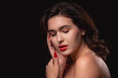 Parlak makyajlı güzel bir kadın siyah arka planda yalnız poz veriyor..