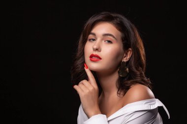 Parlak makyajlı güzel bir kadın siyah arka planda yalnız poz veriyor..