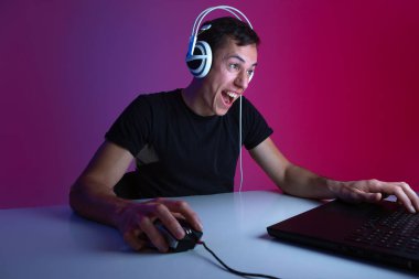 Kulaklık takan heyecanlı bir oyuncu karanlık bir odada neon ışıklarıyla bilgisayar başında oyun oynuyor.. 