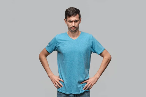 Уверенный в себе человек в синей футболке, смотрящий вниз, держась за руки на бедрах. Концепция доверия . — стоковое фото