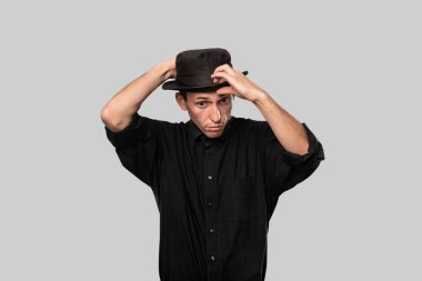 Tarz sahibi yakışıklı bir adam. Gri arka planda siyah bir gömlek ve domuz pastası şapkası.