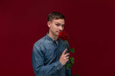 Genç adam sevgilisine vermek için elinde kırmızı bir gül tutuyor. Sevgililer gününde hediye hazırlıyorum..