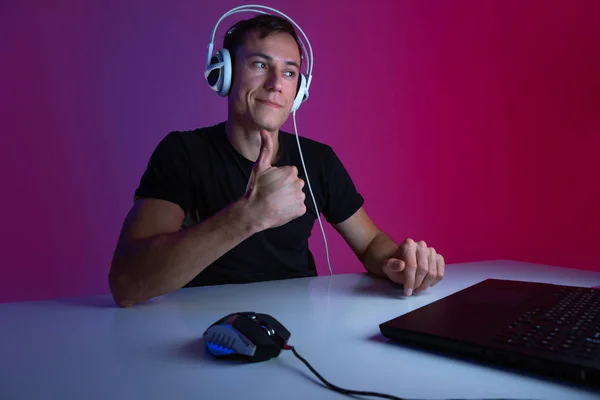 Kulaklıklı heyecanlı oyuncu karanlık bir odada neon ışıklarla aydınlatılmış bir video oyununda kazandığı için mutlu..