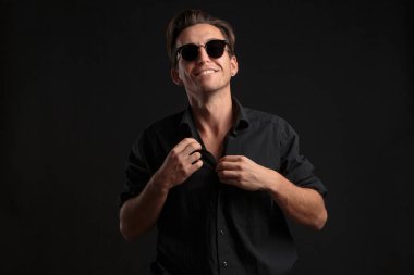 Siyah gözlüklü, kendine güvenen, siyah arka planda izole edilmiş balkon gömlekli adam..