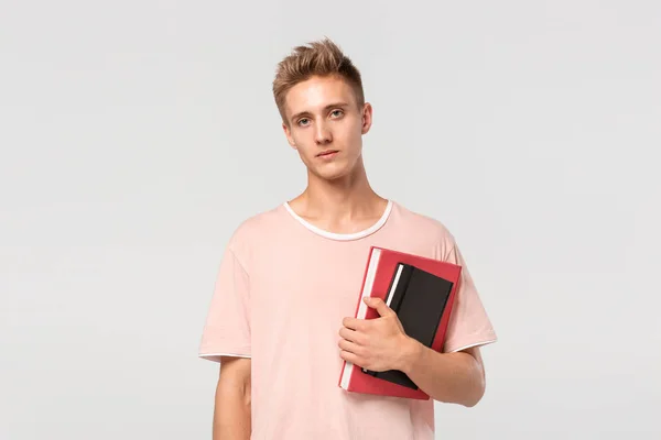 Söt ung man i rosa t-shirt med böcker och filer. — Stockfoto