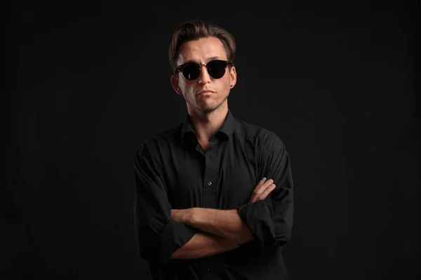 Confident stylish man in black eyeglasses isolated over black background.