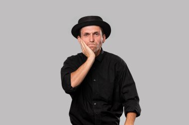 Tarz sahibi yakışıklı bir adam. Siyah gömlek ve domuz turtası şapkası. Gri arka planda izole edilmiş sorunları var..