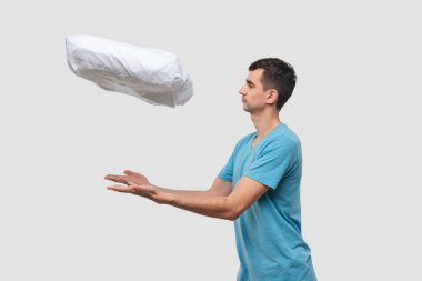 Mavi tişörtlü yakışıklı esmer adam yastığı havaya kaldıran shwoing büyüsü yapıyor..