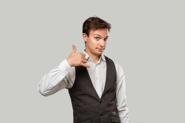 Joven empresario con camisa blanca y chaleco gris pidiéndole que lo llame con un gesto de mano — Foto de Stock