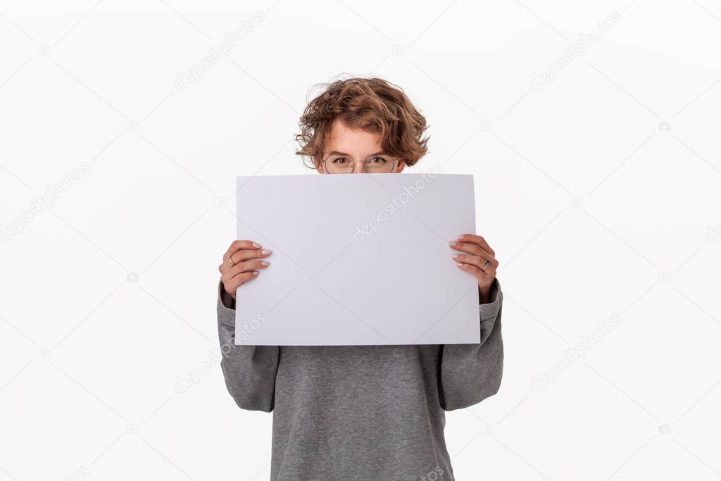 Pretty young woman holding empty blank paper board with copy space for text