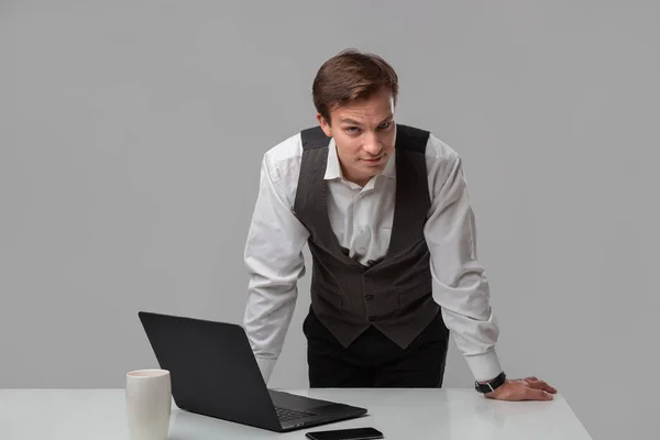Empresario con camiseta blanca y chaleco gris trabajando en un portátil — Foto de Stock