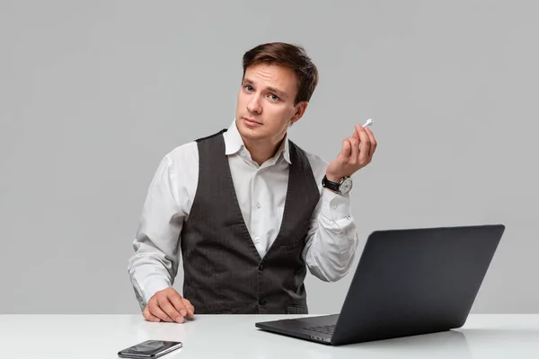 Hombre con una camiseta blanca y chaleco gris se quita los auriculares para escuchar mejor — Foto de Stock