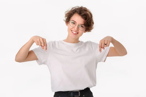 Mujer bastante sonriente con camisa blanca y anteojos apuntando al espacio de copia — Foto de Stock