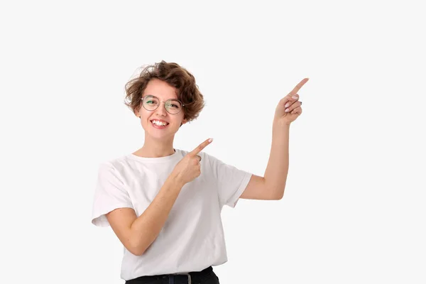 Красивая улыбающаяся женщина в белой рубашке и очках, указывающая на пространство для копирования — стоковое фото