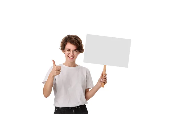 Smiling young woman holding empty signboard with copy space and showing thumb up. Imagen de archivo